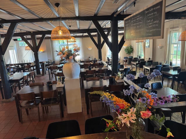 Sfeervolle zaal met bloemen op tafel en zicht op het gazon